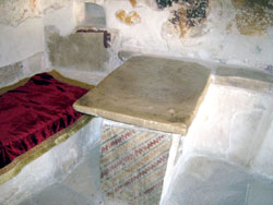 В келье преподобного Неофита выбитый его руками в скале стол соседствует с таким же каменным лежаком